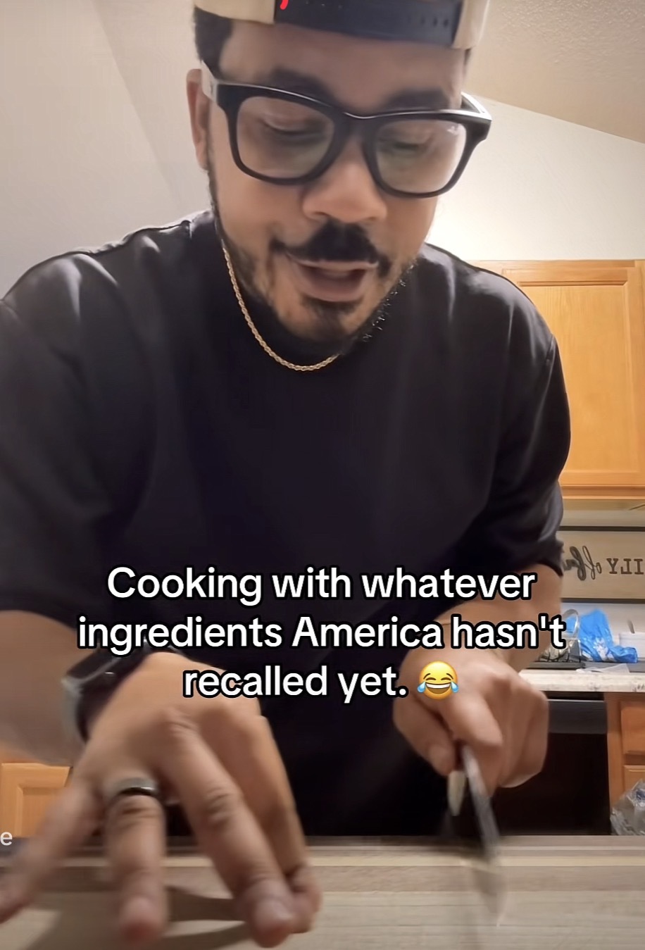 A person using a knife on an empty cutting board with the caption, “Cooking with whatever ingredients America hasn't recalled yet.”
